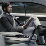 A man in a suit reading a book inside a modern luxury car, showcasing Rocky Mountain Commercial Real Estate.