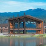 Modern building in Delta County, showcasing wood and metal design, surrounded by mountains and water.
