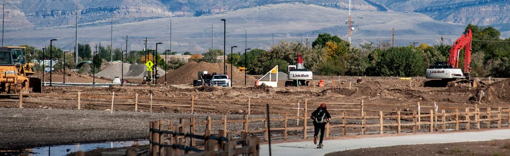 Construction site with vehicles, a pedestrian, and LinkBot signage in Grand Junction, Colorado for RMCRE's market insights.