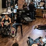 Tattoo artists and clients in a modern studio highlighting artistic expression in Aspen real estate context.