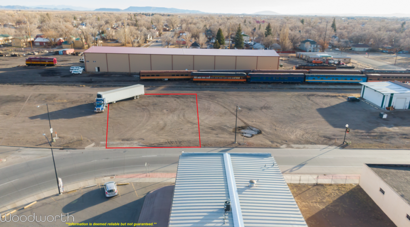 12,000 square foot commercial lot for sale in downtown Alamosa, Colorado, featuring high-traffic visibility, surrounded by industrial and residential areas, with a truck parked nearby.