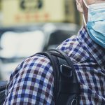 Person in a face mask and plaid shirt in a busy Aspen setting, showcasing commercial real estate developments by RMCRE.