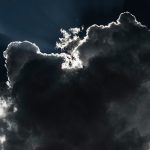 Dark clouds with light peeking through, illustrating the dramatic atmosphere of Colorado's commercial real estate market.