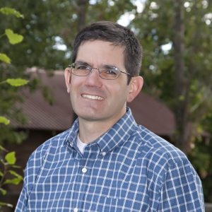 Smiling middle-aged man in glasses outdoors, representing approachable brokers at Rocky Mountain Commercial Real Estate.