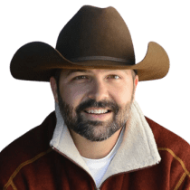 Smiling real estate agent Justin Osborn in a cowboy hat and red jacket, showcasing his approachable demeanor.
