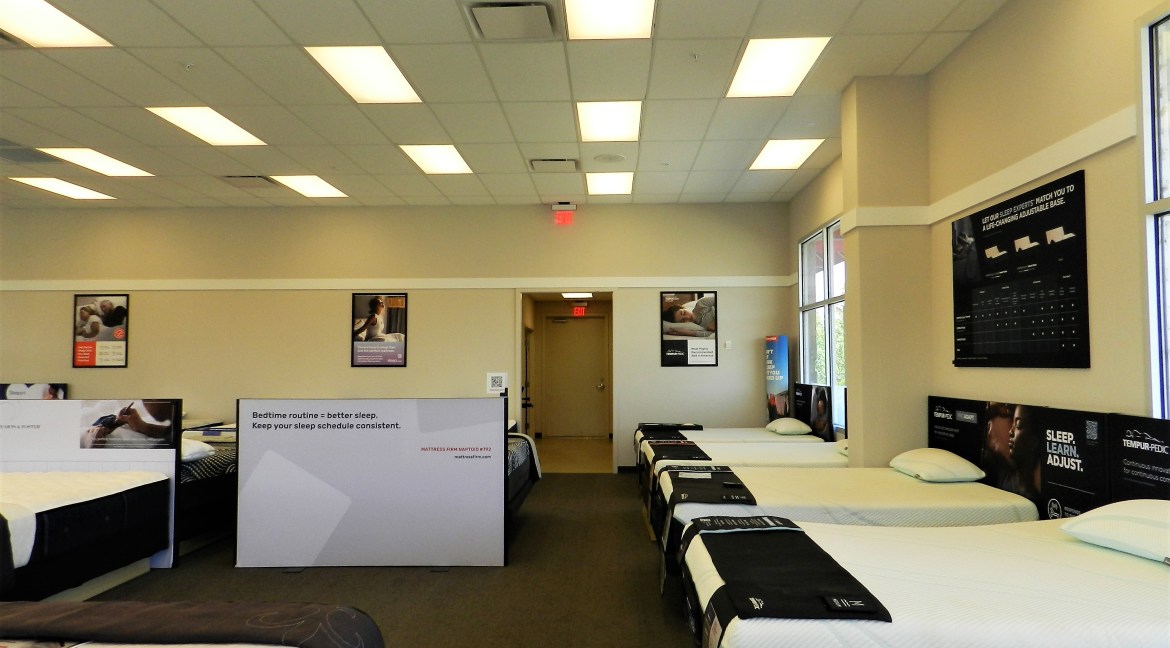 Showroom interior of a mattress retail store featuring multiple display beds, promotional signage about sleep routines, and a welcoming layout for customers.