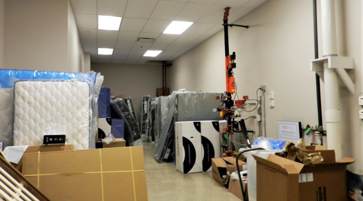 Storage area filled with wrapped mattresses, boxes, and equipment, showcasing the interior of a commercial property for sale at 3501 Wolverine Dr, Montrose, Colorado.