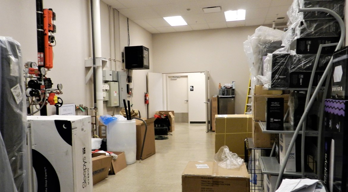 Storage area of a commercial retail/office building featuring stacked boxes, equipment, and fire suppression system, highlighting the space's utility for business operations at 3501 Wolverine Dr, Montrose, Colorado.