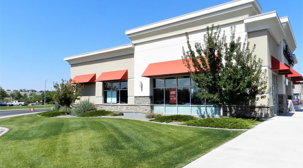 Commercial retail building for sale at 3501 Wolverine Dr, featuring large windows, red awnings, landscaped surroundings, and ample parking, located in high-traffic area of Montrose, Colorado.