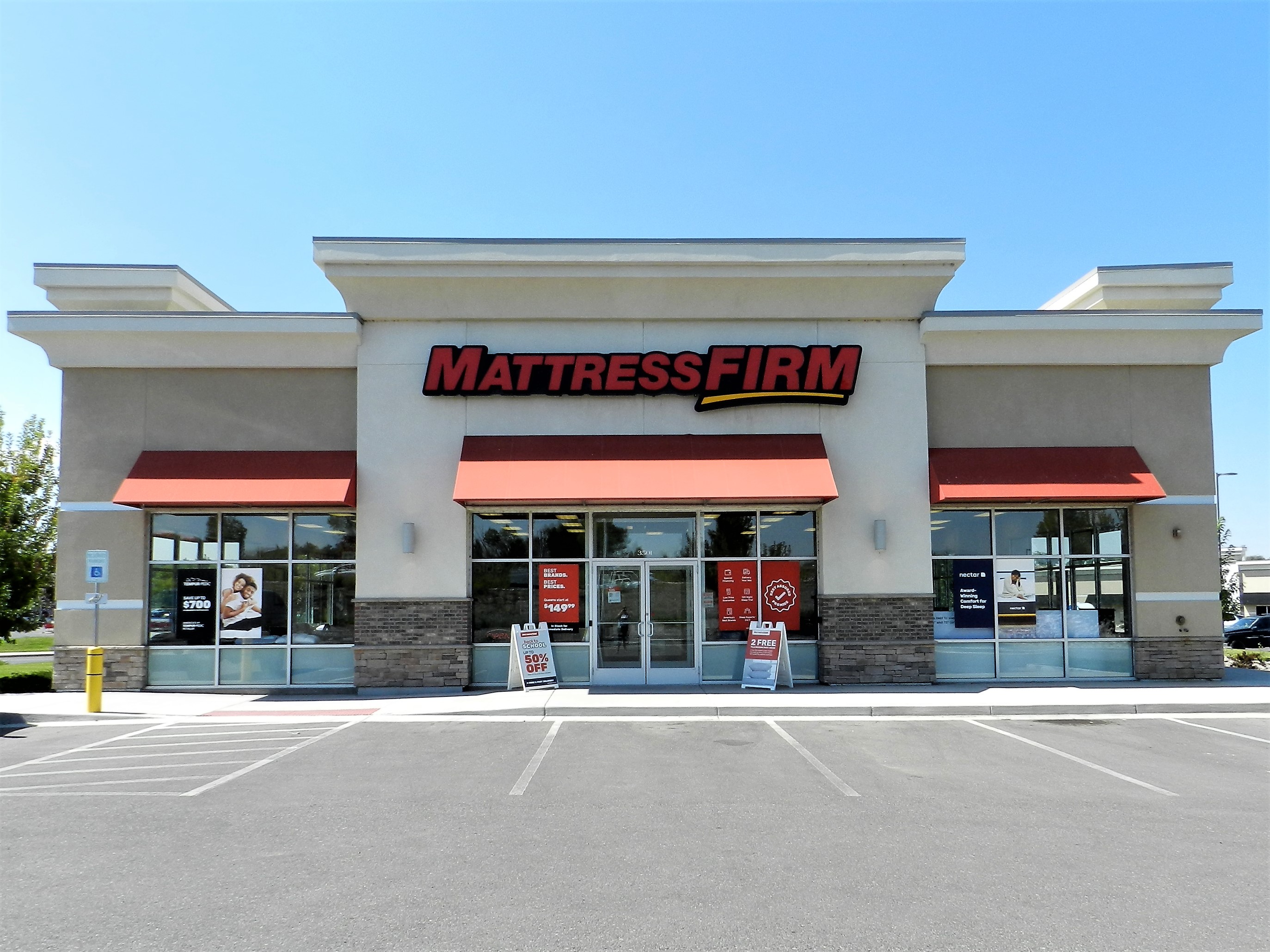 Commercial retail building exterior featuring Mattress Firm signage, large windows displaying promotional offers, and ADA accessibility, located in a busy commercial corridor in Montrose, Colorado.
