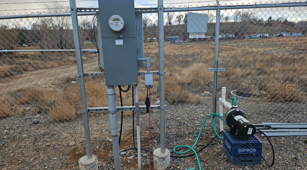 Utility meter and pump equipment on fenced commercial land, with dry grass and gravel in the background, near 65 Circle Dr., Delta, Colorado, zoned B-3 for development opportunities.