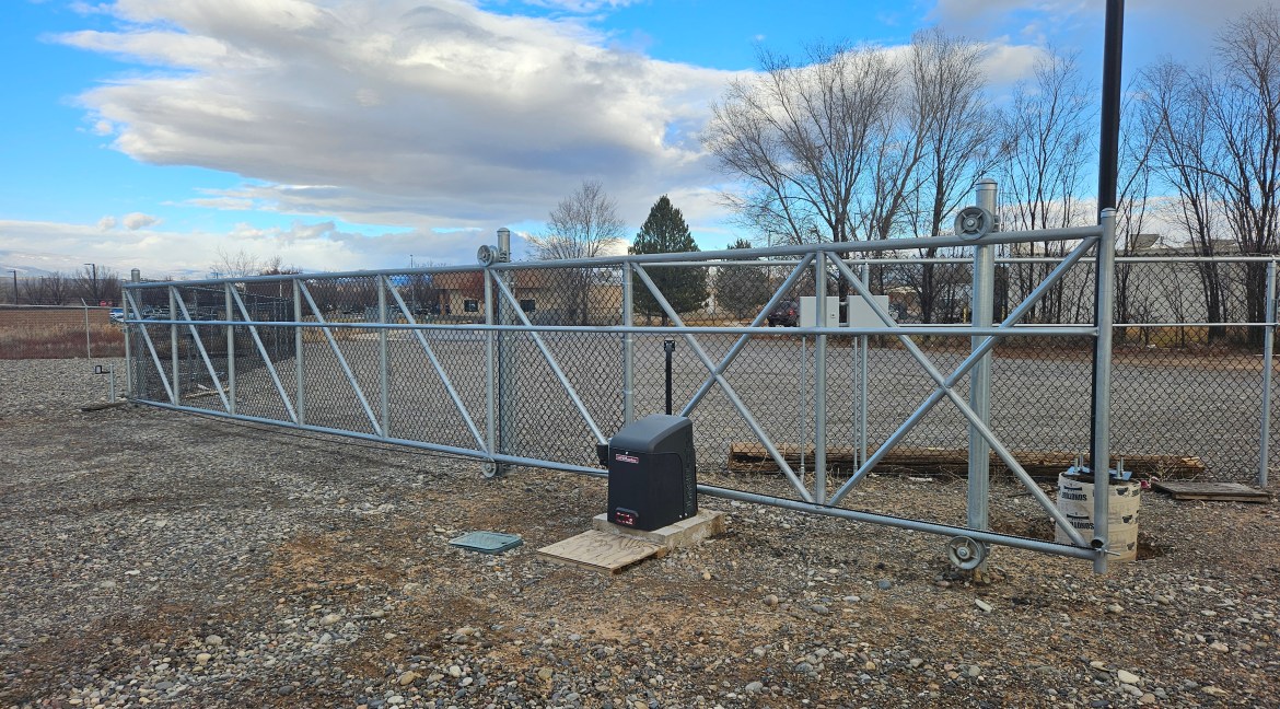 Automated security gate with chain link design and control panel, situated on commercial land at 65 Circle Drive, Delta, Colorado.