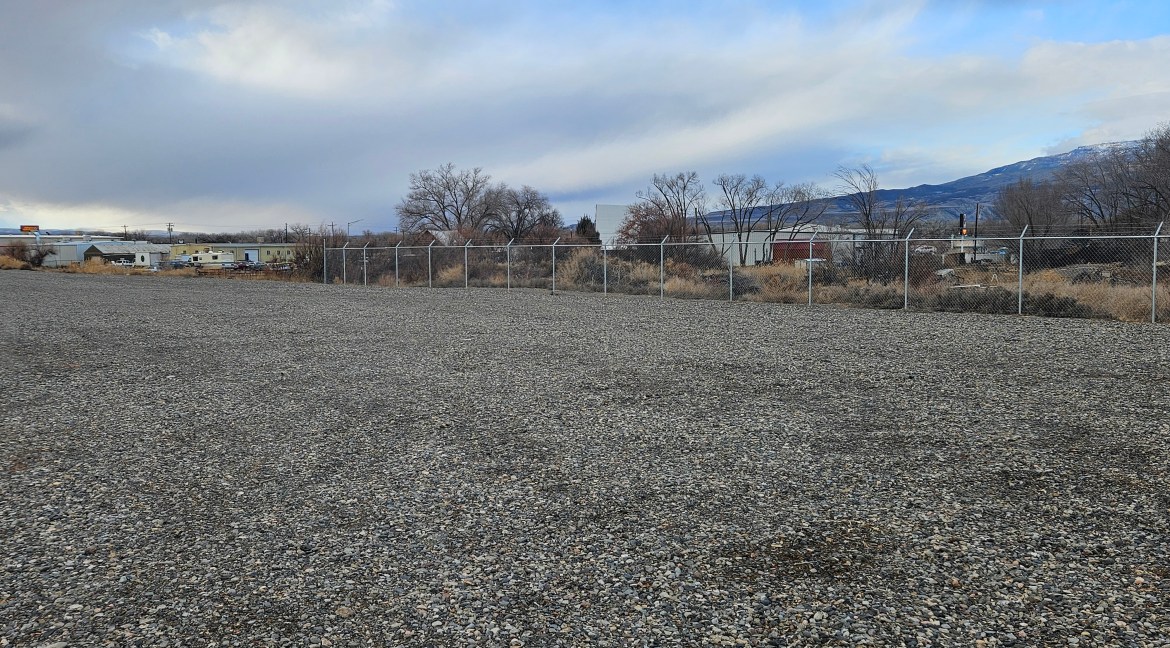 4.34 acres of partially improved land with B-3 zoning, featuring gravel surface and fenced perimeter, located near commercial establishments in Delta, Colorado.