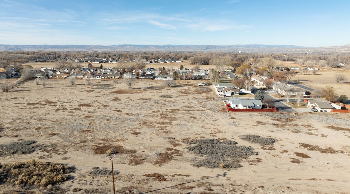 Aerial view of a 14.84-acre residential development parcel in Delta, Colorado, showcasing nearby residential areas and open land, highlighting investment potential for future development.