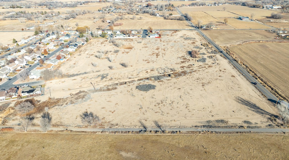Aerial view of approximately 14.84 acres of vacant land for residential development near TBD G Road, Delta, CO, showcasing proximity to residential neighborhoods and road access.