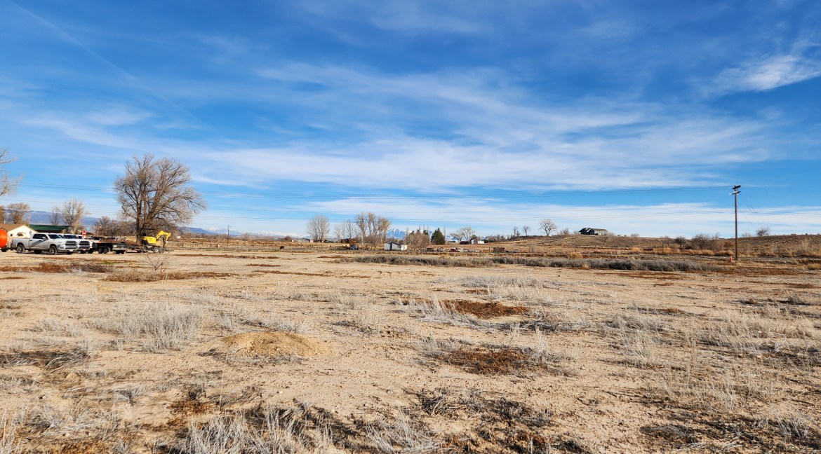 14.84-acre residential development land in Delta, Colorado, featuring open terrain, distant structures, and clear blue sky, suitable for investment and development opportunities.