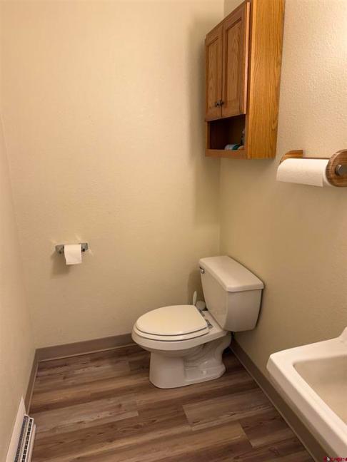 Bathroom interior featuring a toilet, wall-mounted cabinet, and towel holder, showcasing the well-maintained condition of the commercial property for sale in Alamosa, Colorado.