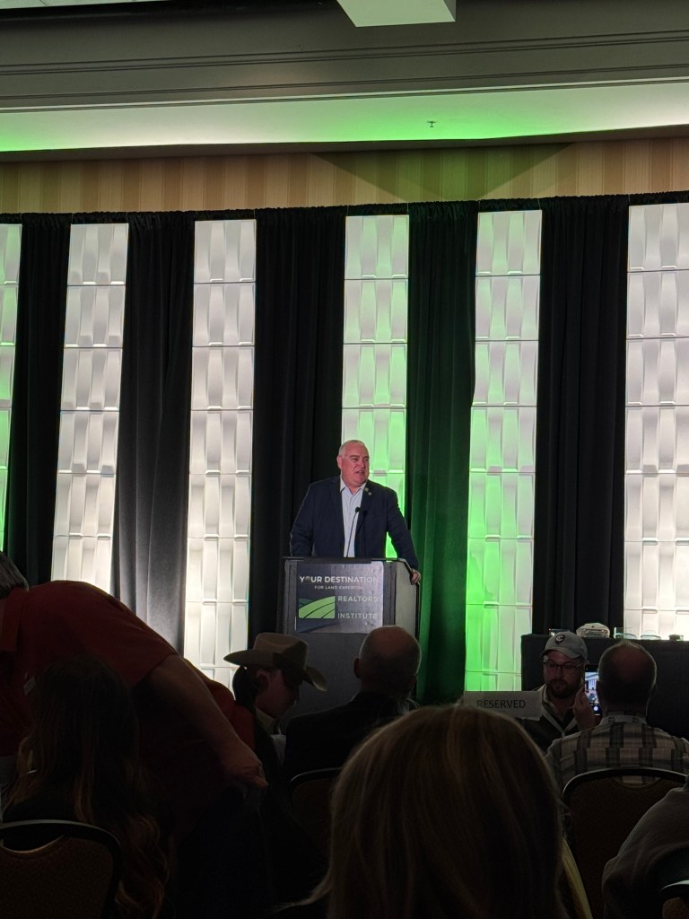 Speaker at RLI National Land Conference 2025 in Tucson, AZ, addressing audience with focus on land education and networking, backdrop featuring RLI branding and event decor.