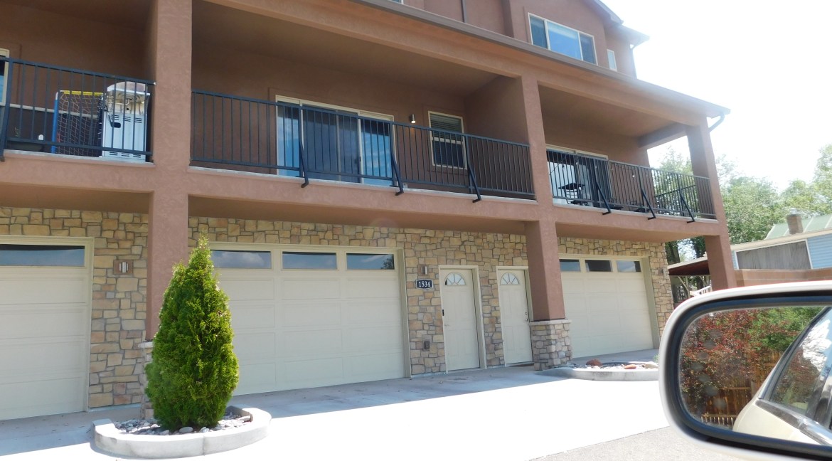Modern townhome exterior at 1534 Poplar Drive, featuring stone and stucco facade, balconies, and garages, showcasing contemporary design in Grand Junction, Colorado.