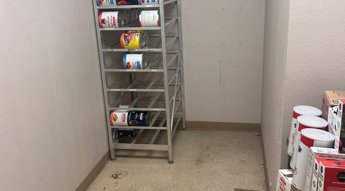 Commercial kitchen storage area featuring metal shelving with canned goods, highlighting organizational space for food preparation and inventory management.