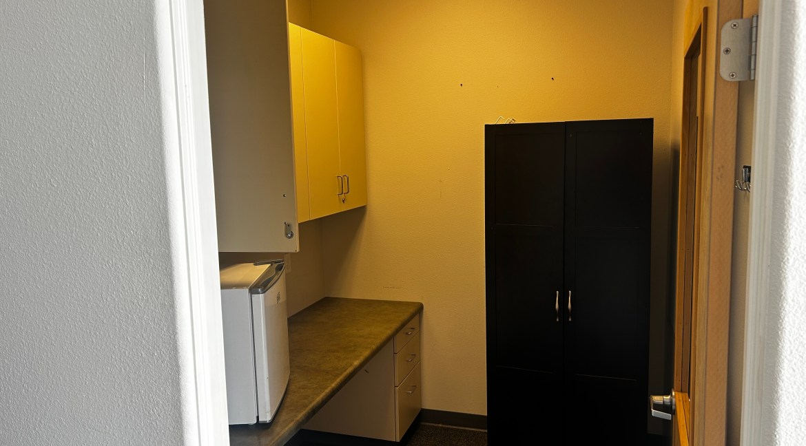 Commercial kitchen storage area featuring yellow cabinets, a black storage unit, and a small refrigerator, designed for efficient food service operations at 350 Stafford Lane, Delta, Colorado.