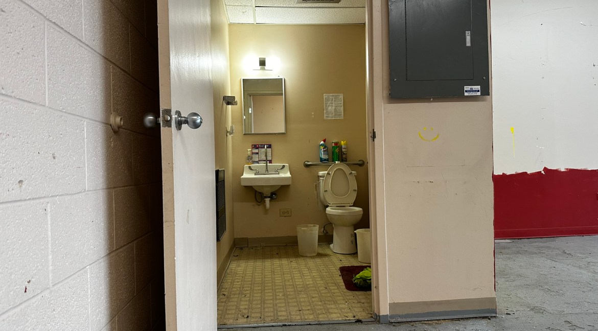 Bathroom interior with sink, toilet, and cleaning supplies, located in retail unit at Coronado Plaza Shopping Center, Clifton, Colorado.